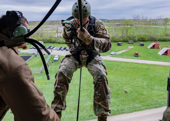 A man in a military uniform is suspended from a harness
