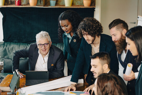 Diverse team of architects and designers working on a project using a digital tablet and blueprints