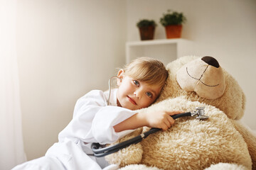 Doctor, kid and play with stethoscope on teddy bear for medical or cardiology education in home....
