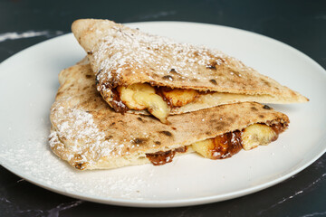Italian dessert - calzone filled with chocolate, banana and powdered sugar