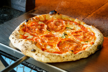 Taking out a fried pizza from an Italian pizza oven