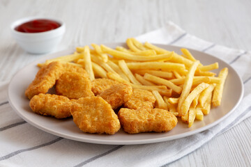 Fried Chicken Nuggets with French Fries on a Plate, side view.
