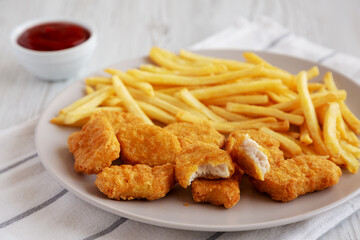 Fried Chicken Nuggets with French Fries on a Plate, side view.