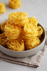 Raw Dry Tagliatelle Pasta in a Bowl, side view.