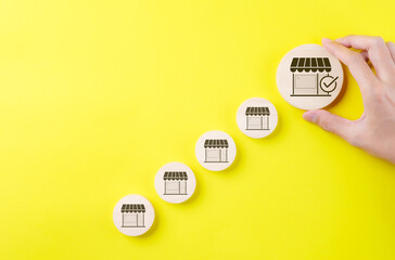 Business expansion and franchise growth concept. Hand selecting large store icon among smaller ones...