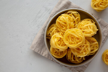 Raw Dry Tagliatelle Pasta in a Bowl, top view. Flat lay, overhead, from above. Copy space.