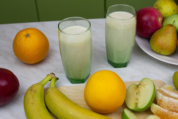 Sports cocktail with fruits and milk in glass cup on table of home kitchen. Simple recipe of milkshake with vitamins to improve health and immunity