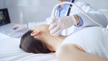 Doctor man is using ultrasound equipment on neck of female patient lying down for a medical examination. Medicine and science