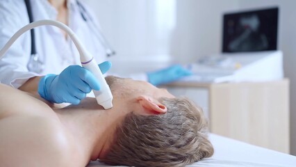 Doctor woman with a blue medic gloves performing neck ultrasound exam on male patient. Medicine service concept. Thyroid gland health