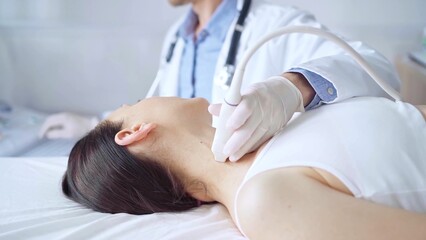 Doctor man is using ultrasound equipment on neck of female patient lying down for a medical examination. Medicine and science