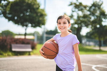 girl child in sportswear playing basketball game
