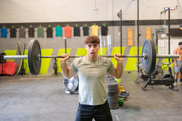 Man lifting barbell with weights in gym during strength training.