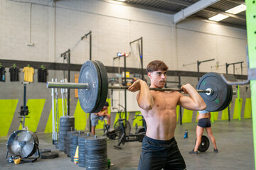 Young man lifting barbell in gym with focused expression
