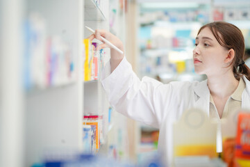 woman pharmacist checks and arranges medicines on pharmacy shelves, emphasizing precision and responsibility in healthcare services. The scene highlights the daily operations in a modern pharmacy.