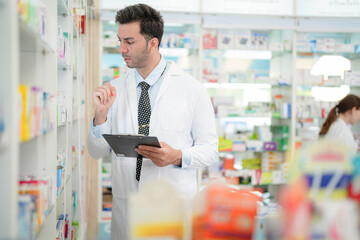 man pharmacist checks and arranges medicines on pharmacy shelves, emphasizing precision and responsibility in healthcare services. The scene highlights the daily operations in a modern pharmacy.