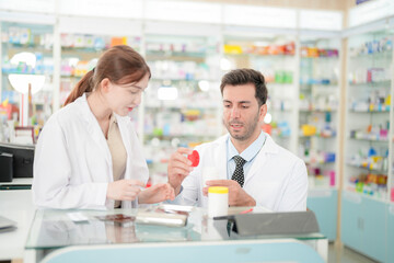 Obraz premium team man and woman pharmacist inspects a medication bottle, ensuring accuracy in prescription filling. pharmacists in patient safety and careful medication handling. operations in retail pharmacy.