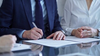 Business people wearing suits signing important documents during a corporate meeting. Win-win concept