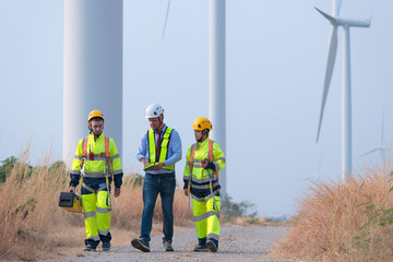 Group of service engineers discussing against turbines on wind turbine farm. engineers with tool against turbines on wind turbine farm.