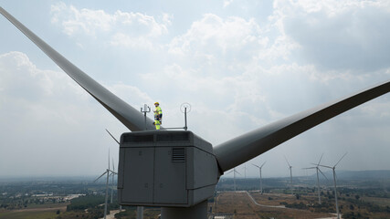 Wind mill engineer wearing PPE standing on wind turbine.  engineer feel success after good work. He...