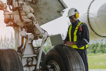 Mechanics inspect the engines of a large plane before takeoff at a summer airport.