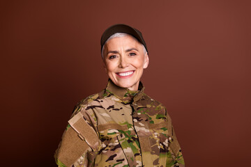 Photo of strong cheerful elderly lady dressed camo uniform smiling empty space isolated brown color...
