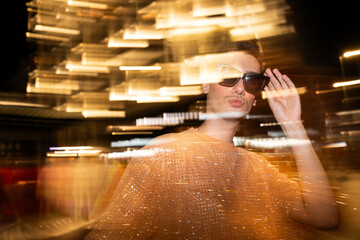 Non-binary Individual poses amid dynamic light streaks