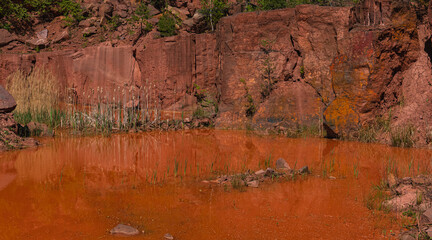Landscape of an abandoned red sandstone quarry with water filling its bottom