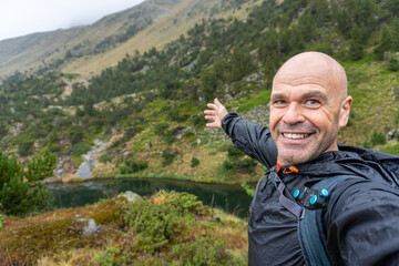 Man in raincoat takes a selfie hiking on a rainy winter day on mountains, in Pirineos, Huesca...