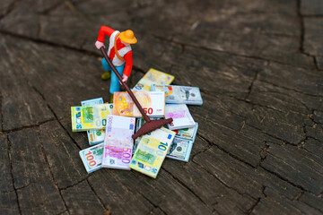 Toy Gardener Raking Money Piles on Rustic Wooden Surface