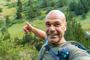 Smiling man with thumbs-up takes a selfie hiking outdoors