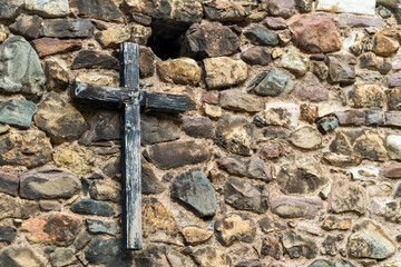 Wooden old cross hanging on a stone wall
