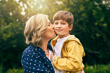 Mother, happy son and outdoor portrait with kiss, vacation and support in relationship connection. Boy, mom and together for security embrace in countryside, trust and affection in England for peace