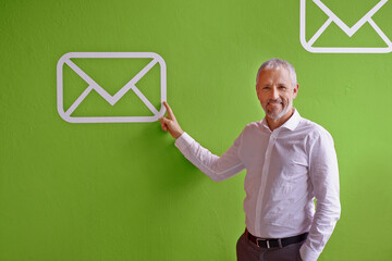 Mature, happy man and portrait with email, icon or envelope for communication, message or online service. Businessman, employee or pointing with smile or symbol for presentation on green background