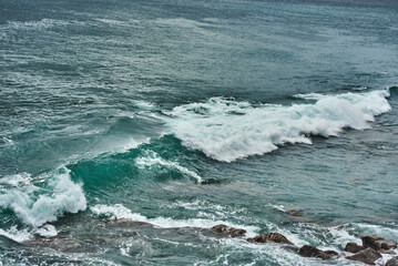 An ocean wave is crashing over the rocky cliffs