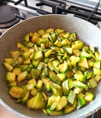 Preparation of zucchini salad in a frying pan.
finely chopped zucchini is fried in a pan on the stove. close-up, home cooking.