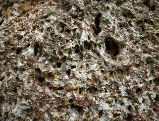Old grey stone wall with many hole for abstract seamless background and texture. beautiful patterns, space for work, close up.