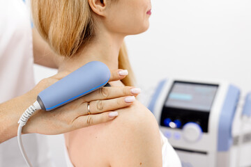  A young woman receives electromagnetic therapy in a modern clinic. This treatment enhances tissue...