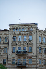 Obraz premium A detailed view of a historic, ornate apartment building with multiple floors, balconies adorned with flowers, and various window styles, against a clear blue sky. 