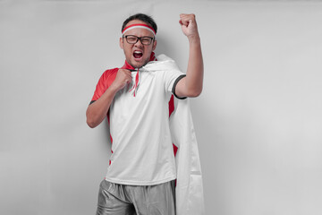 Energetic young Asian man wearing jersey with flag draped over shoulder raising hand in the air.