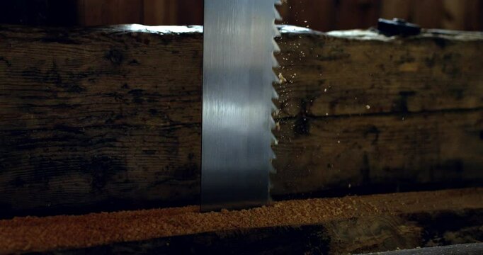 Super slow motion close up of artisan carpenter is working on wood surface with hacksaw with flying wood chipping shaving pieces and sawdust at his workshop at 1000 fps.