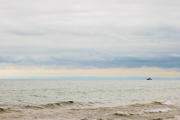 Far on the horizon of Lake Michigan, a lone fishing boat plies the water under the opening skies from the storm clouds