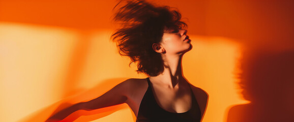 Studio portrait of woman dancing with motion blur effect and orange background	
