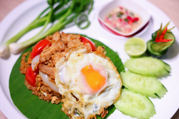 Thai style fried rice with meat, tomatoes, onions, fried egg, fish sauce and various vegetables side dish.
