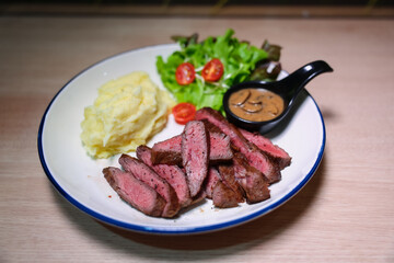 Medium rare steak, cut into bite-sized pieces, served with pepper sauce, mashed potatoes and salad.