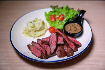 Medium rare steak, cut into bite-sized pieces, served with pepper sauce, mashed potatoes and salad.
