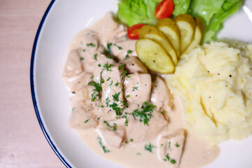 Chicken in cream sauce served with mashed potatoes and salad.