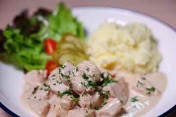 Chicken in cream sauce served with mashed potatoes and salad.