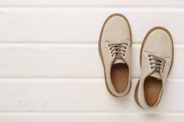 Beige suede shoes on wooden background, top view