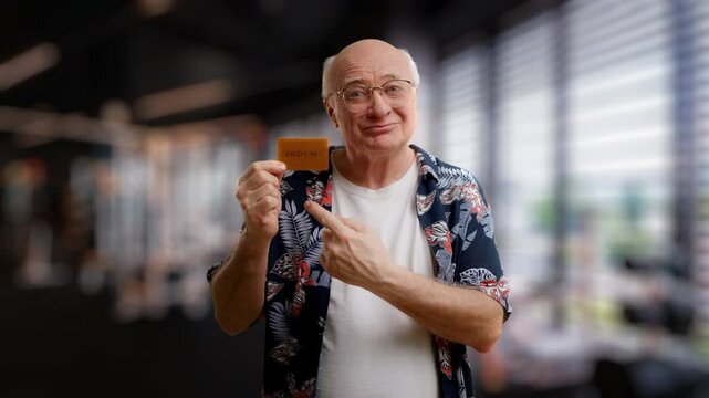 Smiling grandpa in glasses showing gold credit card, deposits and investments
