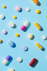 Flat Lay of Colorful Medication on Blue. Overhead view of assorted colorful medication on blue background, suitable for healthcare themes.